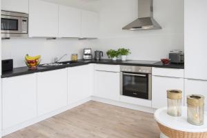 a white kitchen with black counter tops and appliances at Oceanhouse in Olpenitz