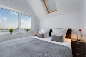 a white bedroom with a large bed with two windows at Viktoria´s Baltic Lounge in Olpenitz