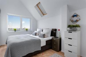 a white bedroom with a bed and two windows at Viktoria´s Baltic Lounge in Olpenitz