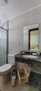 La salle de bains est pourvue de toilettes, d'un lavabo et d'un miroir. dans l'établissement Apartamento 17 San Victor, à Bombinhas