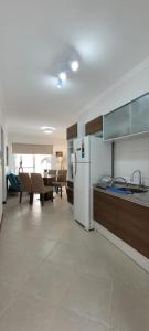 Il comprend une cuisine équipée d'un réfrigérateur blanc et d'une table. dans l'établissement Apartamento 17 San Victor, à Bombinhas