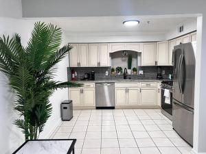 a kitchen with white cabinets and a palm tree in it at Urban Oasis 3 Kings bed 3Mins from EWR-NYC Downtow in Newark