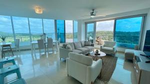 una sala de estar con muebles blancos y ventanas grandes. en 10G Perfect 2 Bedroom with Ocean and Jungle Views, en ArraijÃ¡n