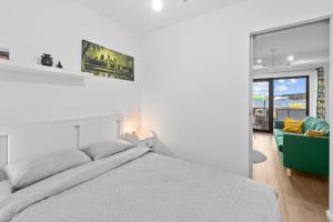 een witte slaapkamer met een bed en een bank bij Ametist Apartment with parking in Floreşti