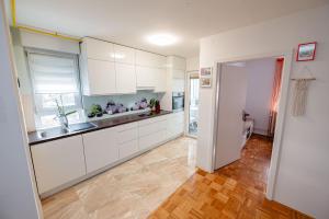 a kitchen with white cabinets and a wooden floor at Apartma Golob in Maribor