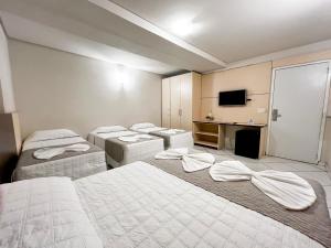 a hotel room with three beds and a television at SMART IGUASSU HOTEL in Foz do Iguaçu