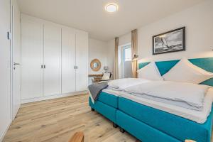 a large blue bed in a bedroom with a wooden floor at Schlei-Koje 1 in Schleswig