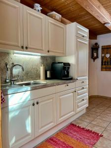 eine Küche mit weißen Schränken und einem Waschbecken in der Unterkunft Umundumhütte in Katsch an der Mur