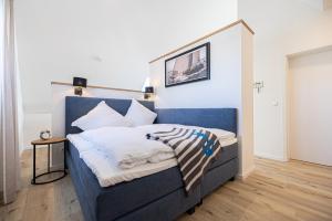 1 dormitorio con 1 cama azul con sábanas blancas en Schlei-Koje 6, en Schleswig