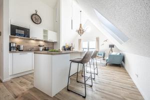 una cocina con armarios blancos y una barra con taburetes en Schlei-Koje 8, en Schleswig