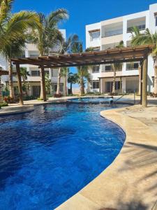 a swimming pool in front of a building with palm trees at Departamento Vacacional en Mazatlán in Mazatlán