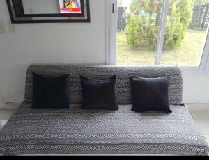 a couch with four pillows sitting in front of a window at La Bendición in Campo Quijano