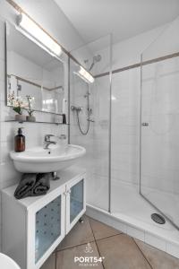 ein weißes Bad mit einem Waschbecken und einer Dusche in der Unterkunft Waterfront 7601 Marina Wendtorf in Wendtorf