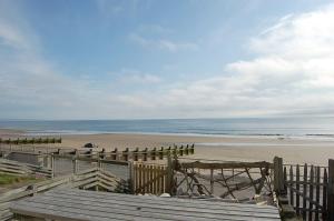 vista su una spiaggia con recinzione e oceano di Chwerthin Y Mor Beach House a Tywyn