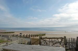 a view of a beach with a fence and the ocean at Chwerthin Y Mor Beach House in Tywyn