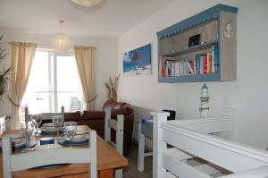 a living room with a table and a dining room at Chwerthin Y Mor Beach House in Tywyn