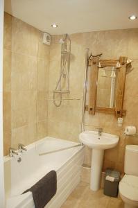 a bathroom with a tub and a sink and a toilet at Chwerthin Y Mor Beach House in Tywyn