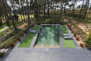 - une vue sur la piscine avec 2 chaises et de la pelouse dans l'établissement Vila Jasmim, à Almada