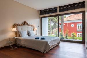 - une chambre avec un grand lit et une grande fenêtre dans l'établissement Vila Jasmim, à Almada