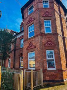 a brick building with a wooden fence in front of it at Cosy Apartment by KS - Free Parking, WIFI, Kitchen, Smart TV, Long stays welcomed! in Hereford