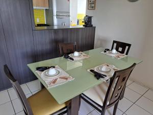 einem grünen Tisch mit Stühlen und Tellern darauf in der Küche in der Unterkunft Apartamento em Maceió com vista para o mar in Maceió