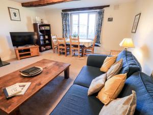 a living room with a blue couch and a wooden table at St Peters Cottage in Milnthorpe