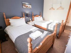 a bedroom with two beds with white sheets at St Peters Cottage in Milnthorpe