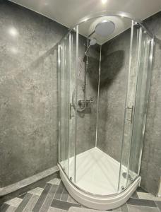 y baño con ducha y mampara de cristal. en Prime Dalgety Bay Waterfront Apartment, en Saint Davids