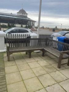 un banc en bois assis devant un parking dans l'établissement Evening Tide, à Herne Bay