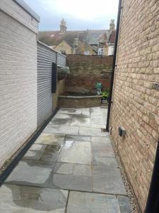 a courtyard with a brick wall and a stone walkway at Evening Tide in Herne Bay