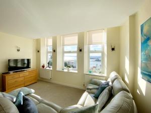 a living room with a couch and a tv and windows at Sea View Apartment, 7 Ellington Court in Torquay