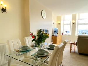 Sea View Apartment, 7 Ellington Court في توركواي: غرفة طعام مع طاولة زجاجية وكراسي بيضاء
