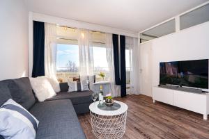 sala de estar con sofá y TV de pantalla plana en Hansa Apartment mit Schwimmbad, direkt am Hansapark, en Sierksdorf