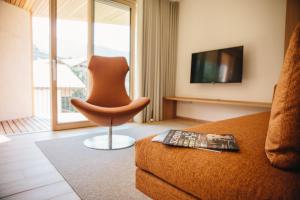 a living room with a couch and a chair and a television at Appartement Steinach in Schenna