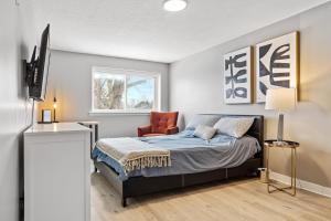 a bedroom with a bed and a chair and a television at 14 minutes from downtown, Luxury home in Nepean in Ottawa