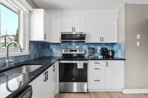 a kitchen with white cabinets and a sink and a stove at 14 minutes from downtown, Luxury home in Nepean in Ottawa