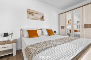 ein weißes Schlafzimmer mit einem großen Bett mit orangefarbenen Kissen in der Unterkunft Ferienwohnung Ostseeinsel Fehmarn in Fehmarn