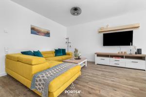 ein Wohnzimmer mit einem gelben Sofa und einem Flachbild-TV in der Unterkunft Ferienwohnung Ostseeinsel Fehmarn in Fehmarn