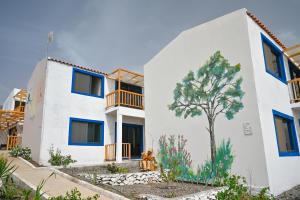 un edificio blanco con un árbol pintado en él en Encosta Azul Guesthouse, en Cidade Velha