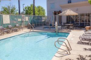 a large swimming pool with chairs and an umbrella at Hilton Garden Inn Redding in Redding