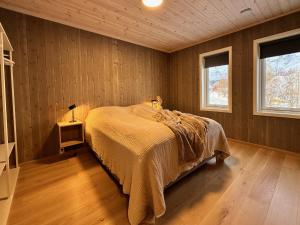ein Schlafzimmer mit einem Bett in einem Zimmer mit Holzwänden in der Unterkunft Superior Ocean View Lofoten in Ballstad