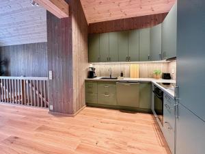 a kitchen with green cabinets and a wooden floor at Superior Ocean View Lofoten in Ballstad