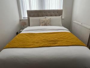 a bed with a yellow blanket on top of it at Charming 1 bedroom Apartment In The Heart Of Manchester Close to Manchester City Centre And Etihad Stadium in Manchester