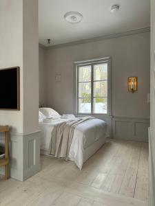 a white bedroom with a bed and a window at Uniikki ja tunnelmallinen empireasunto Hämeenlinnan ydinkeskustassa in Hämeenlinna
