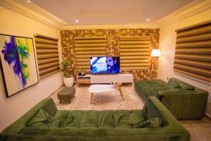 a living room with a green couch and a television at Luxury 3 bed Apartmnt with Minimalist Aesthetic in Abuja