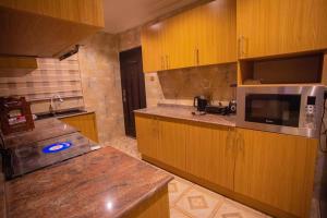 a large kitchen with wooden cabinets and a microwave at Luxury 3 bed Apartmnt with Minimalist Aesthetic in Abuja