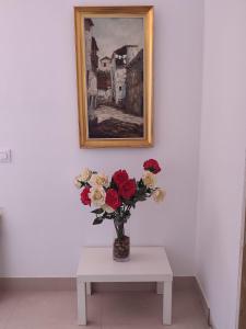 een vaas van rozen op een tafel onder een schilderij bij Las Palmeras 