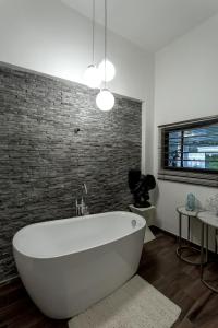a white bath tub in a bathroom with a brick wall at La Caduta Luxury Villa in Livingstone