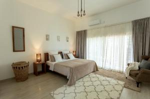 a bedroom with a bed and a chair and a window at La Caduta Luxury Villa in Livingstone
