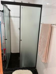 um chuveiro com uma porta de vidro e um tapete na casa de banho em Apart em Miguel Pereira em Miguel Pereira